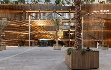 Front view of the Belgian Pavilion with green roof and palm trees.